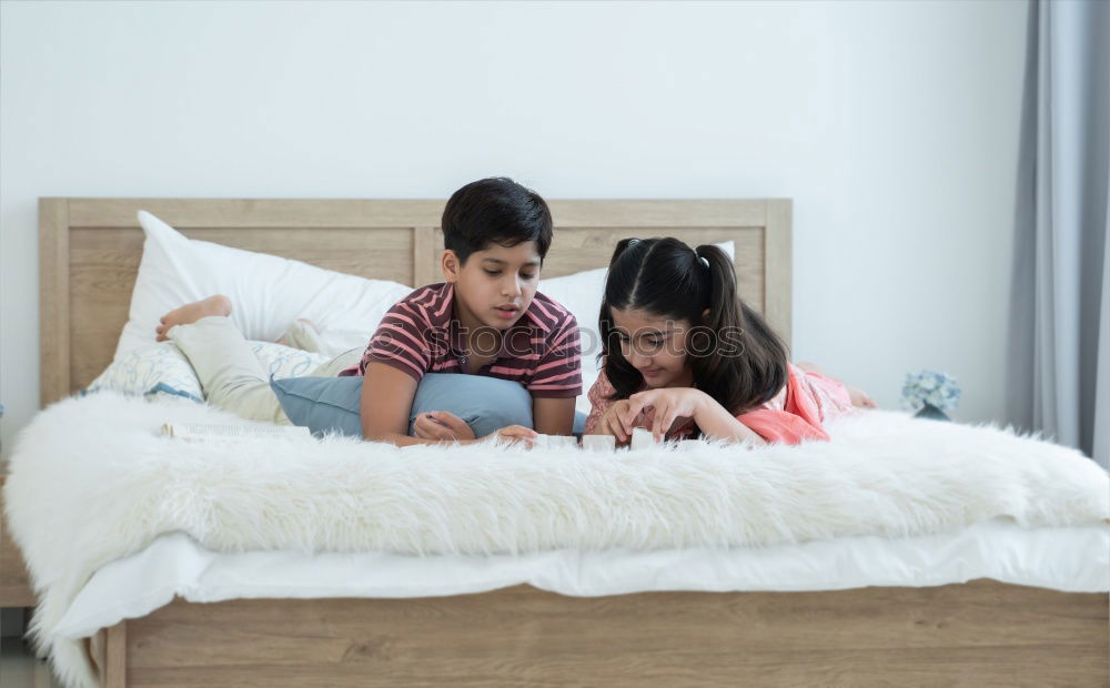 Similar – Image, Stock Photo Girl and boy reading a book sitting on the bed