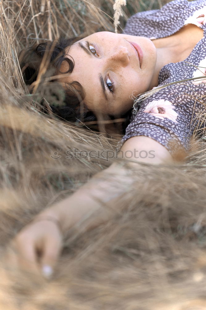 Similar – side portrait of young woman in summer dress sitting barefoot between bushes in nature