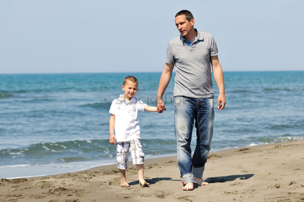 Similar – Image, Stock Photo Smiling father with his young son at the beach crouching down on the sand with a smile as the boy stands alongside him