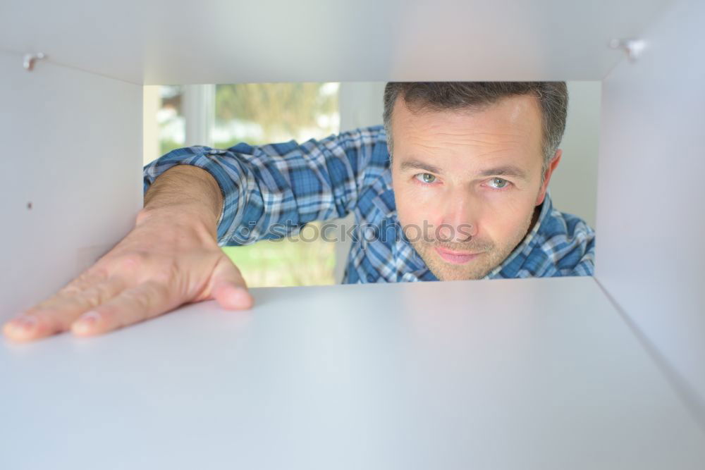 Similar – Young man looks curiously over a barrier