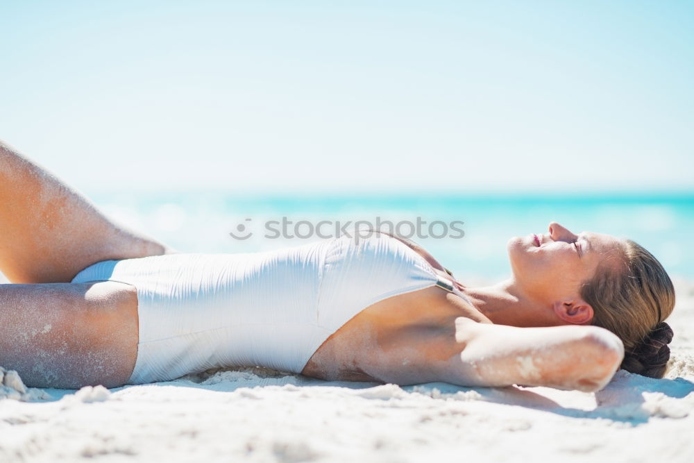 Sexy erwachsene Frau im Badeanzug beim Sonnenbaden am Strand