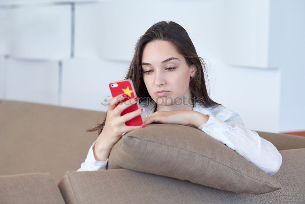 Young girl looking at mobile phone while sitting on bed