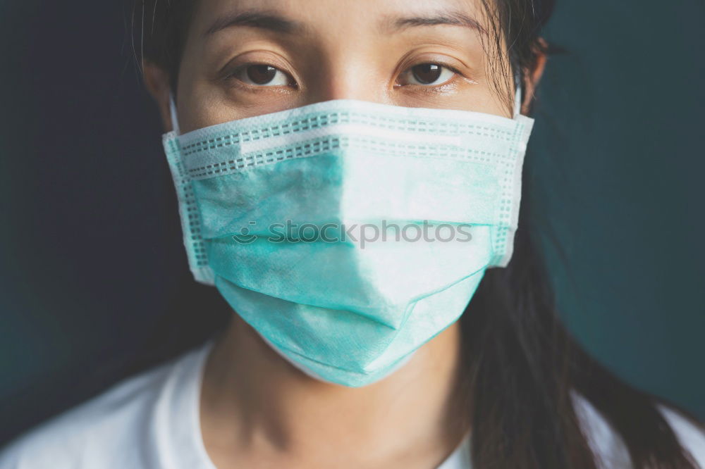 Female Doctor In Face Mask Wearing Scrubs Under Pressure In Busy Hospital During Health Pandemic