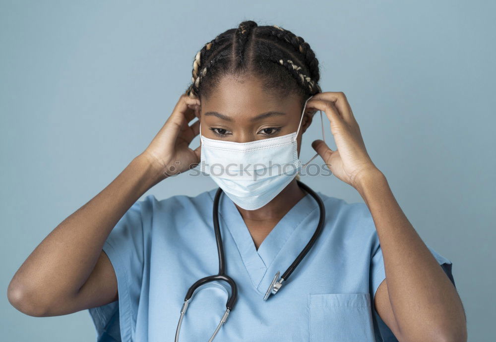 Female Doctor In Face Mask Wearing Scrubs Under Pressure In Busy Hospital During Health Pandemic