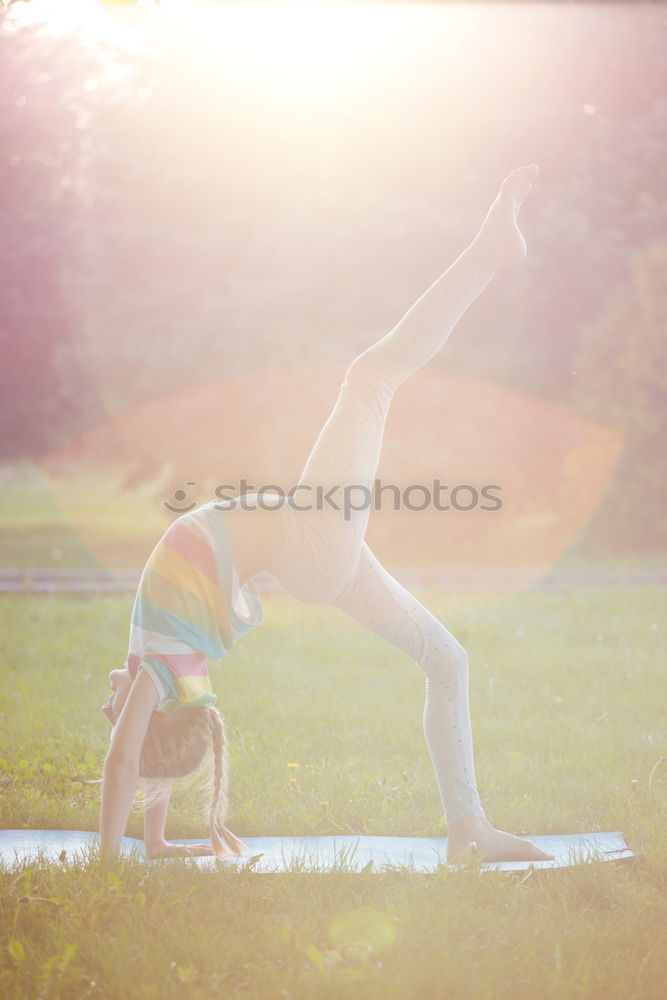 Similar – Agile young woman doing a handstand outdoors in the countryside balancing on her hands with her legs bent in opposite directions