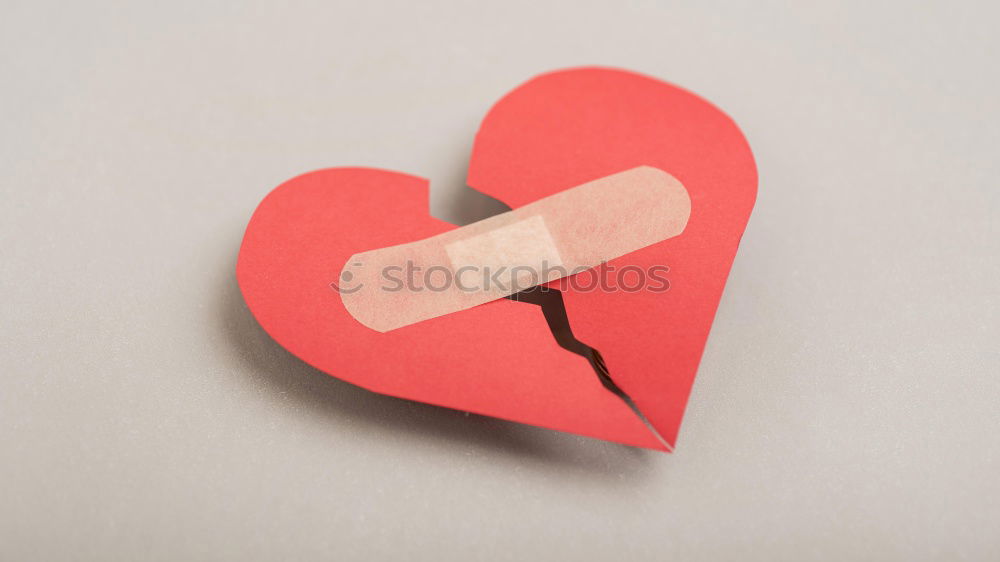 A plaster with a little red heart on it on skin. Concept lovesickness, injury and care.