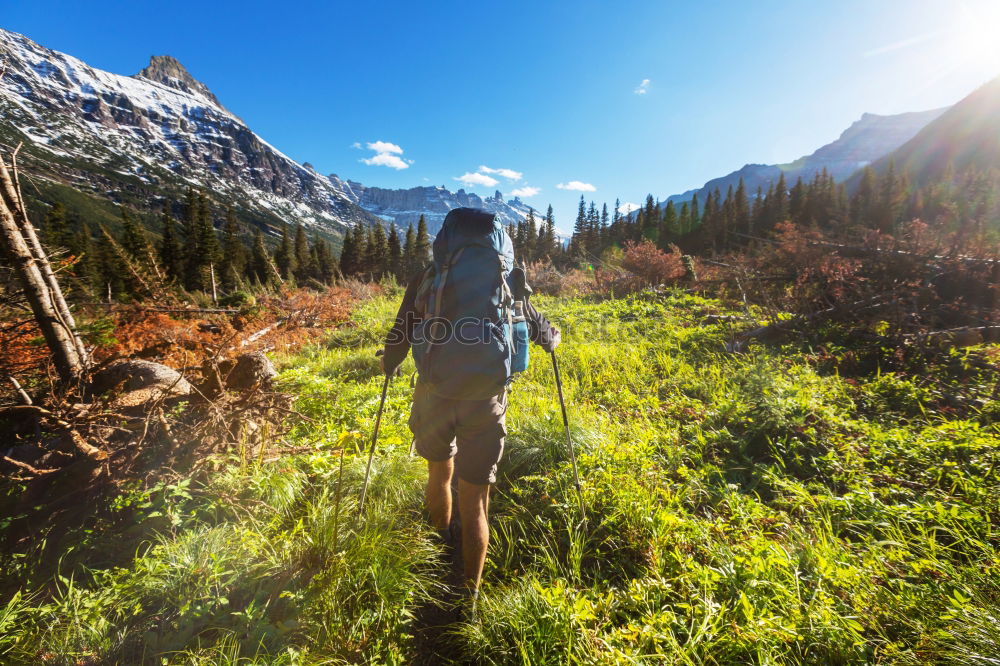 Similar – Cloud rolls over the mountains, man with red jacket and backpack stands on a path and looks into a valley