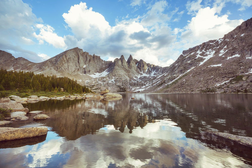 Similar – Wonderful lake between hills in snow and cloudy sky