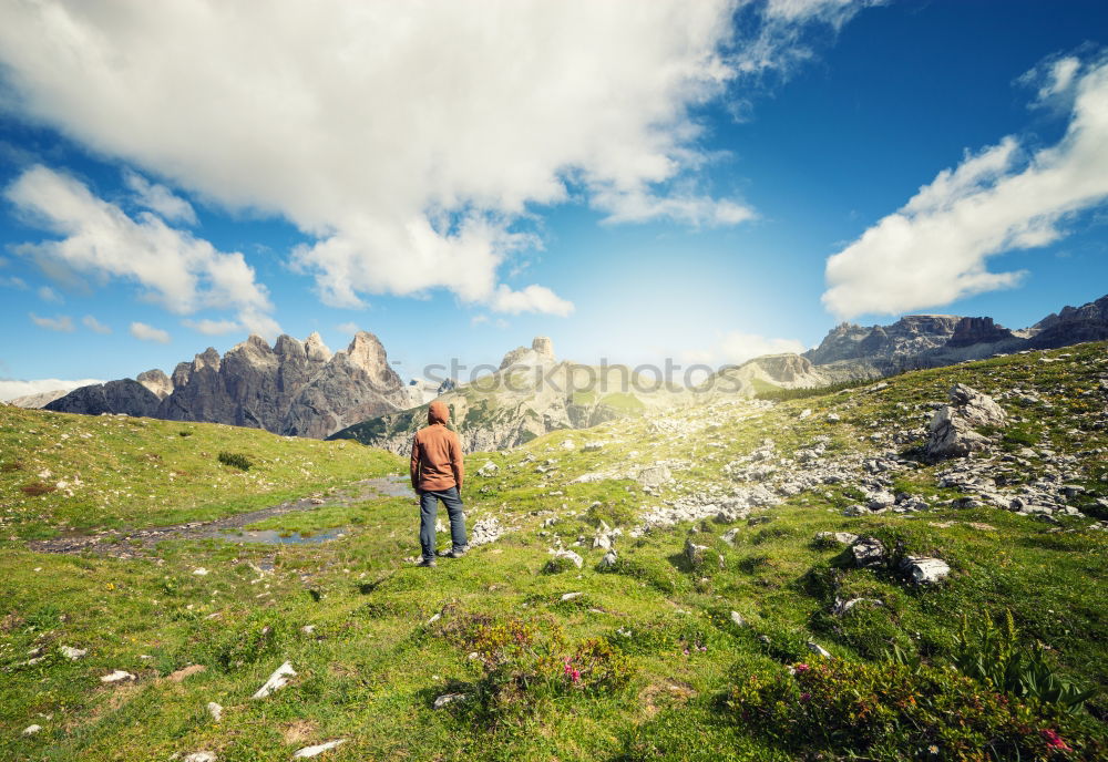 Similar – Cloud rolls over the mountains, man with red jacket and backpack stands on a path and looks into a valley