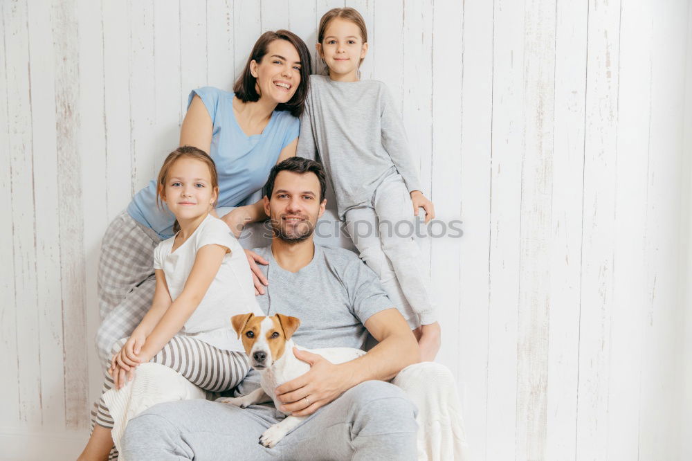 Mature couple relaxed at home in bed with their four little daughters and the Dog