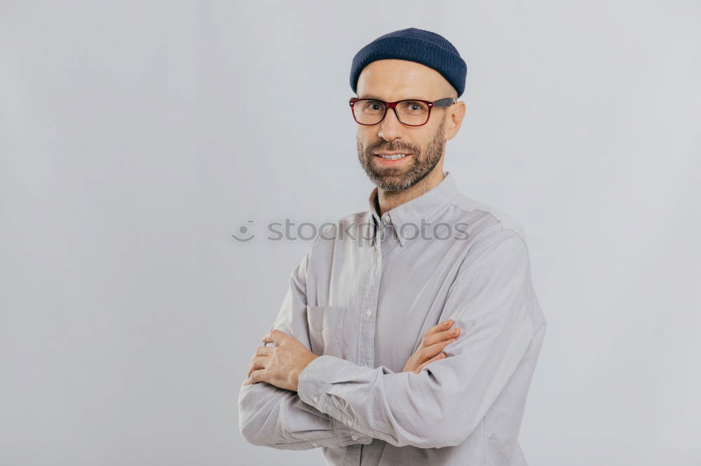 Man with mustache and glasses standing with crossed arms.