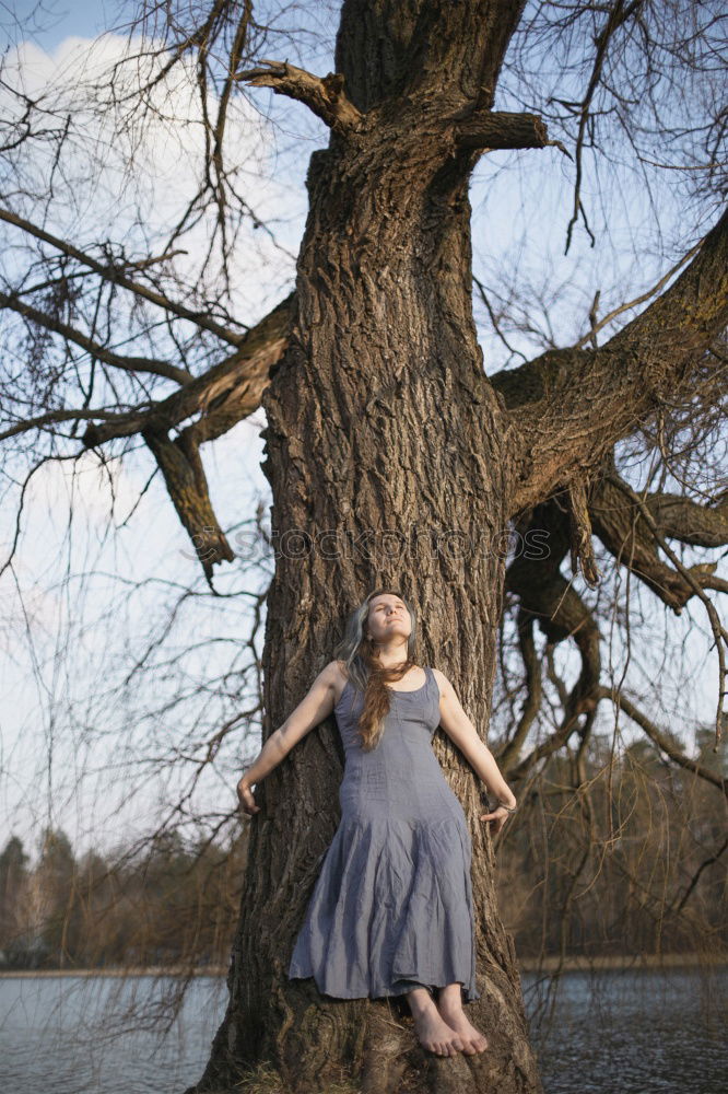 Similar – Young tall woman sitting barefoot by tree in forest in purple wedding dress