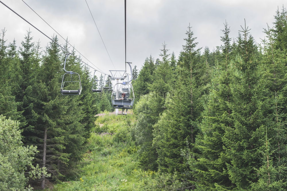 Similar – Chairlift with empty 2-seater chair and view of snow-free hill country