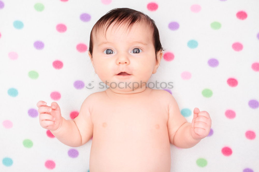 Little baby girl lying on blanket with colourful polka dots