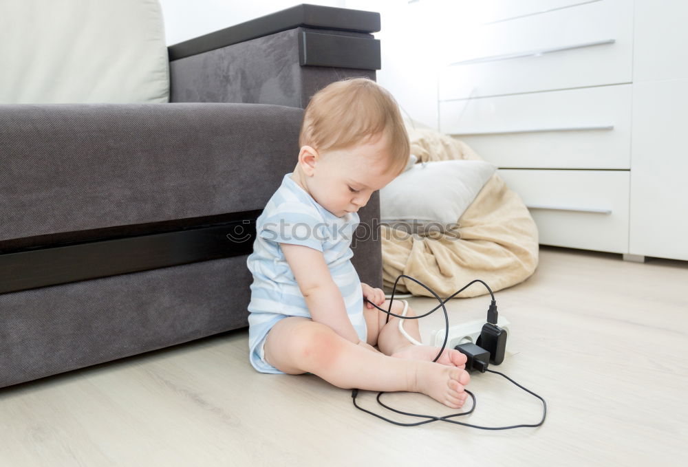 Similar – Baby toddler sits interested and curious in front of washing machine on the floor