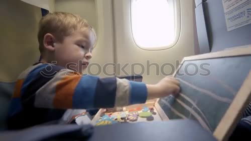 Similar – Image, Stock Photo Little boy sitting in his seat during a flight and painting on a tablet computer in an airplane