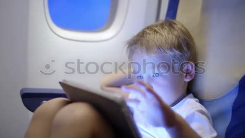 Image, Stock Photo Little boy sitting in his seat during a flight and painting on a tablet computer in an airplane