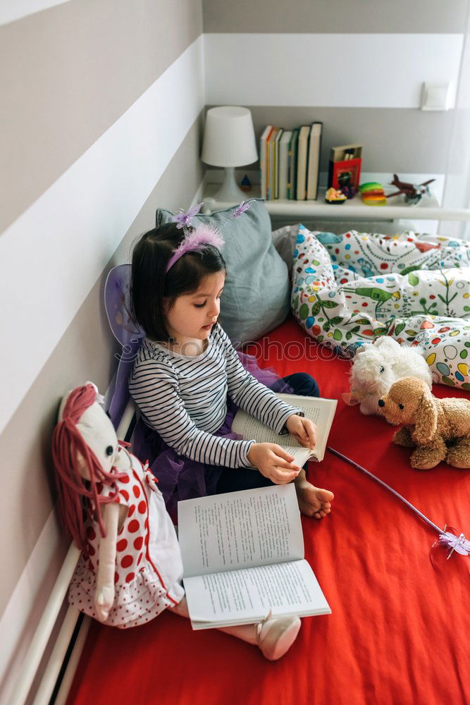 Girl and boy reading book sitting on bed