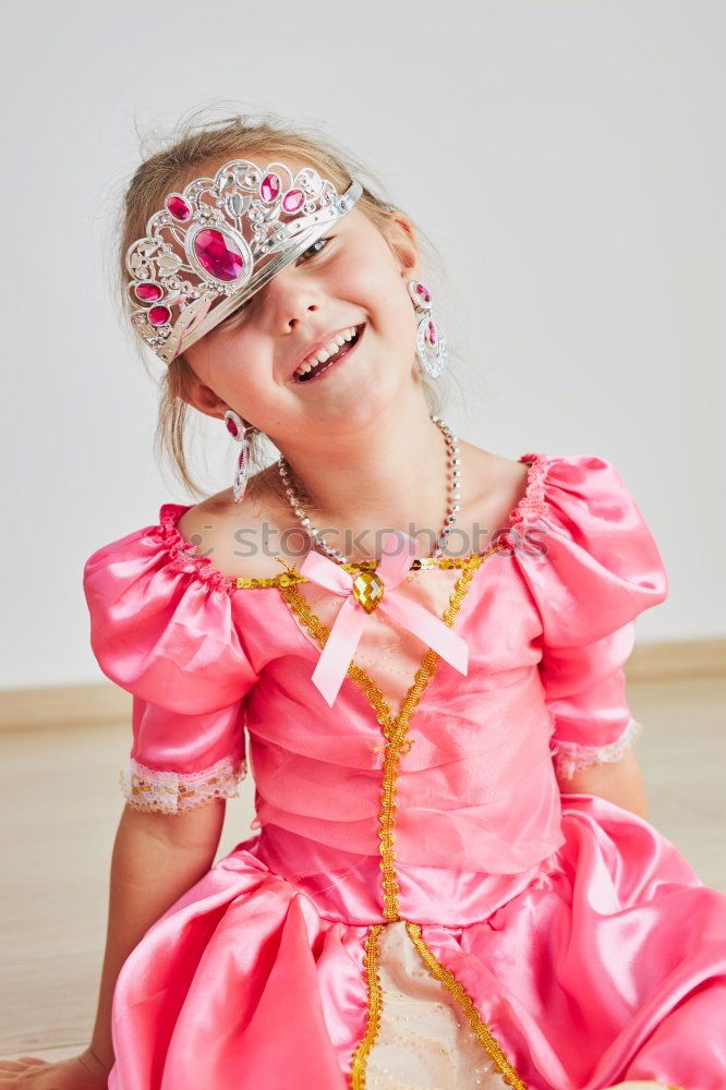 Little girl enjoying her role of princess. Adorable cute 5-6 years old girl wearing pink princess dress and tiara