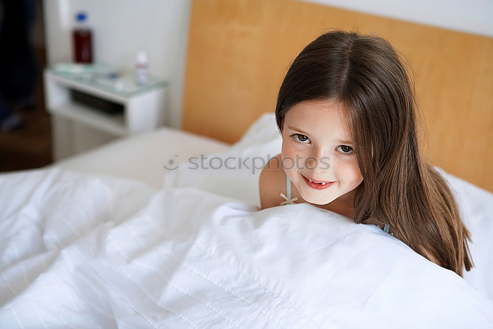 happy child girl sitting on bed and hugs pillow