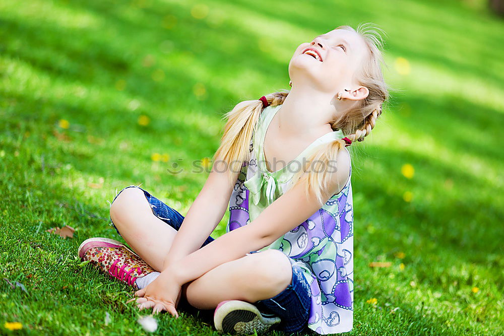 Happy little girl is smiling and  swinging  in the garden in a sunny summer day.