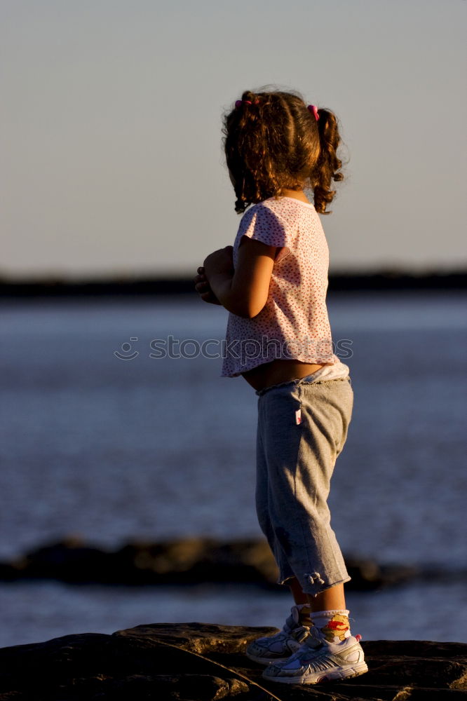 Similar – Child sitting by the sea with a view of a jetty