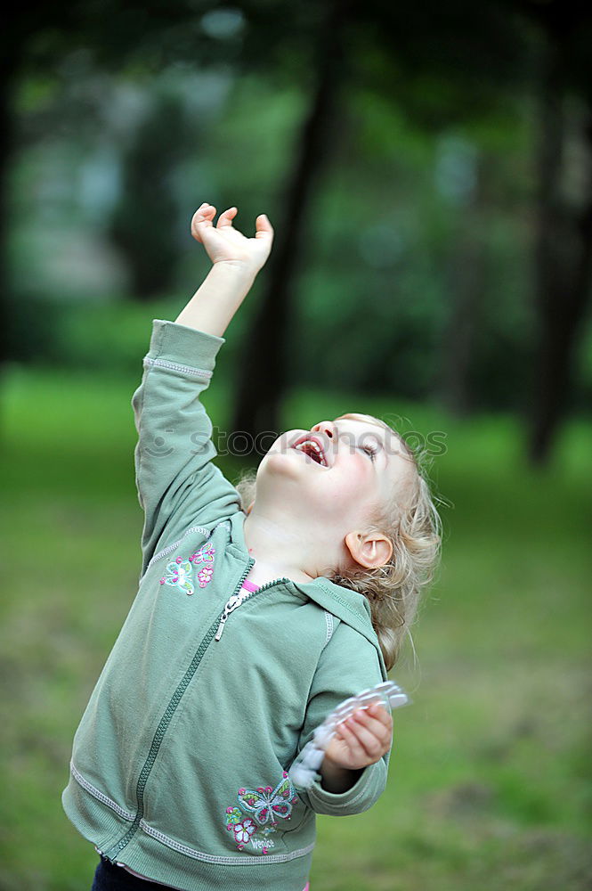 Similar – Image, Stock Photo Funny, funny, cheerful, happy, funny blonde girl outside in the garden, looks up and stretches both arms up to the tree. Little joker does nonsense, sticks out her tongue, in nature, in the park under the tree.