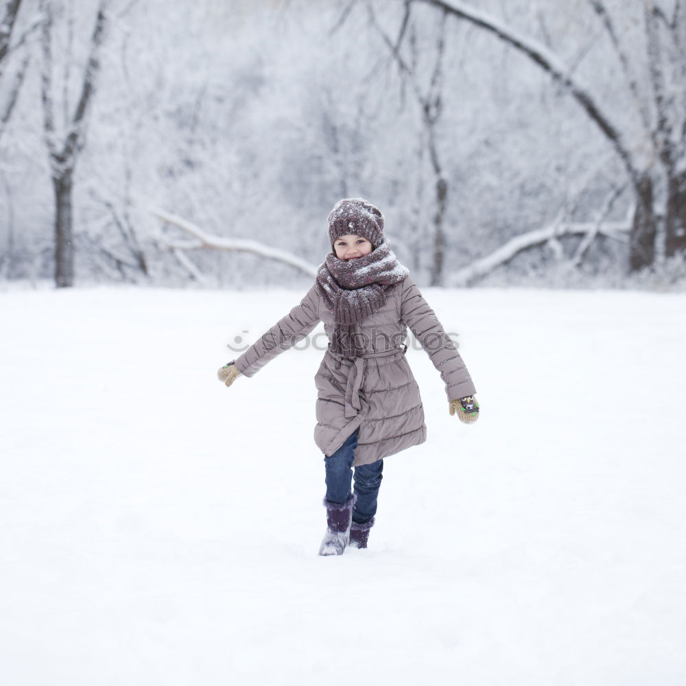 Similar – Family, mother and two daughters, spending time together walking outdoors in winter. Woman is pulling sled with her little daughter, a few years old girl, through forest covered by snow while snow falling, enjoying wintertime. Mother is wearing red winter