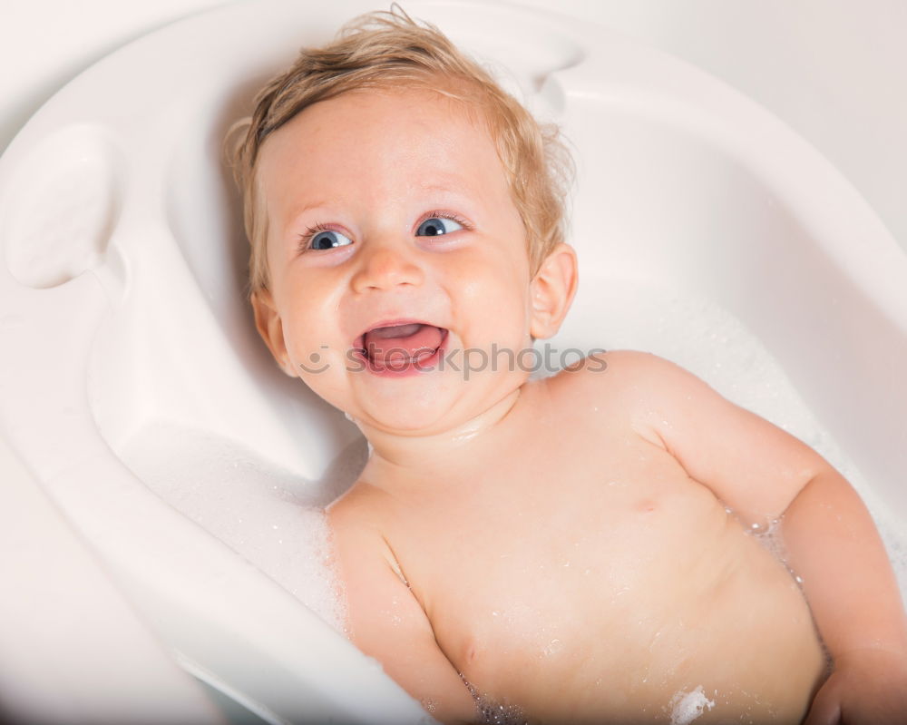 Similar – Baby toddler sits interested and curious in front of washing machine on the floor