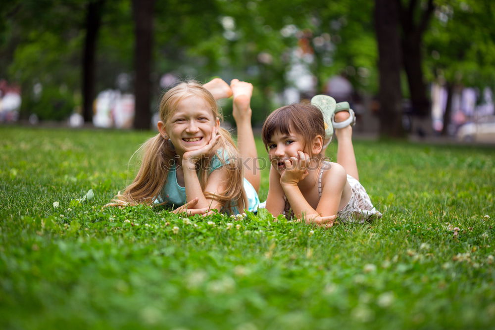 Two happy children playing near a tree on the grass