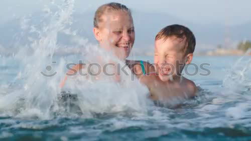 Similar – Laughing little boy flanked by his loving parents paddling together in the shallow water at the edge of the sea