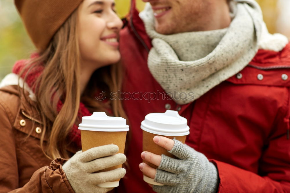 Young couple under blanket having hot drink in a cold day