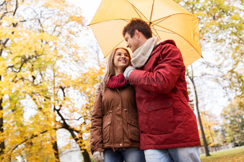 Young couple looking at each other under umbrella outdoors