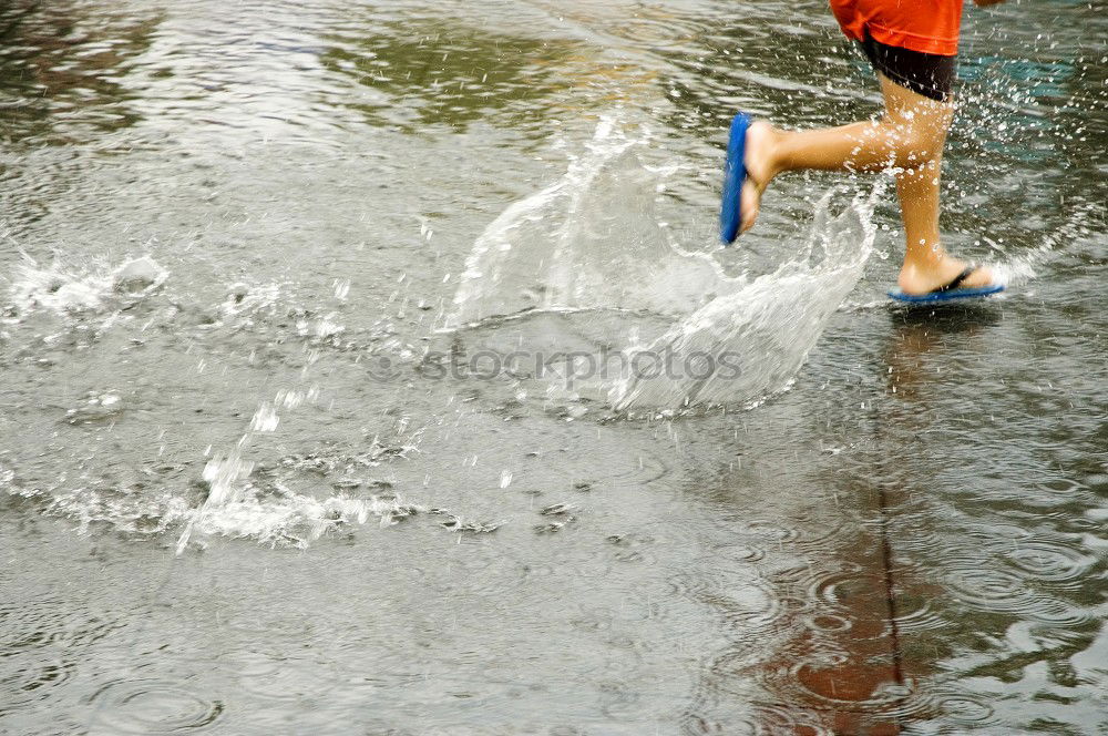 Similar – Little boy jumps into a puddle that makes the water run high