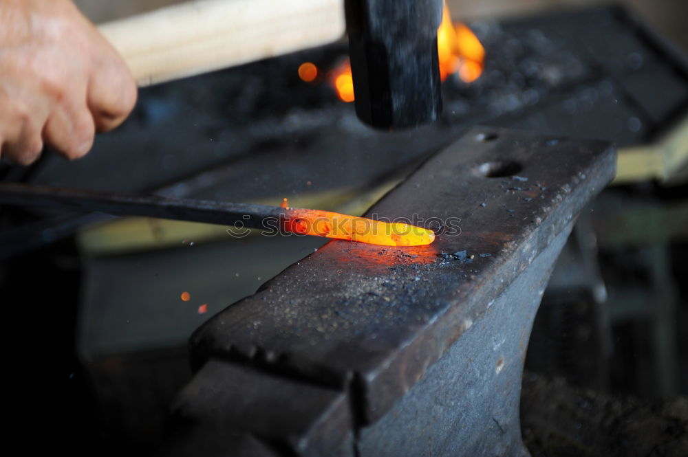 Similar – Blacksmith forges iron on anvil