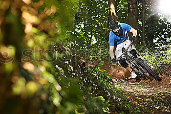 Similar – Biker in Jeans und kariertem Hemd springt mit dem Fahrrad die MTB-Strecke hinunter