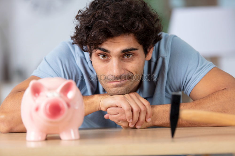 Similar – Unhappy man angry at his piggy bank