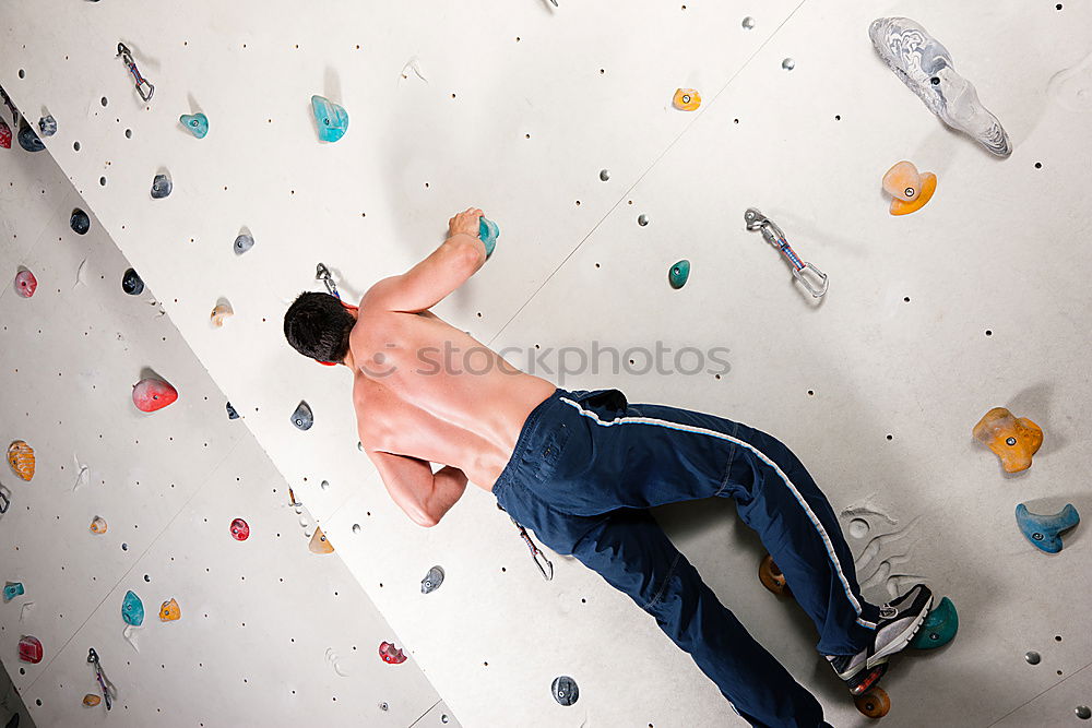 Similar – Man practicing rock climbing on artificial wall indoors.