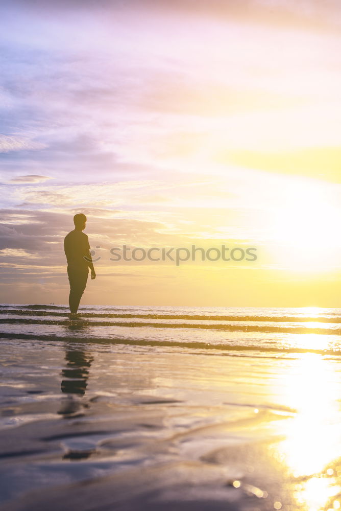 Similar – Man with hat stands in shallow water on the beach