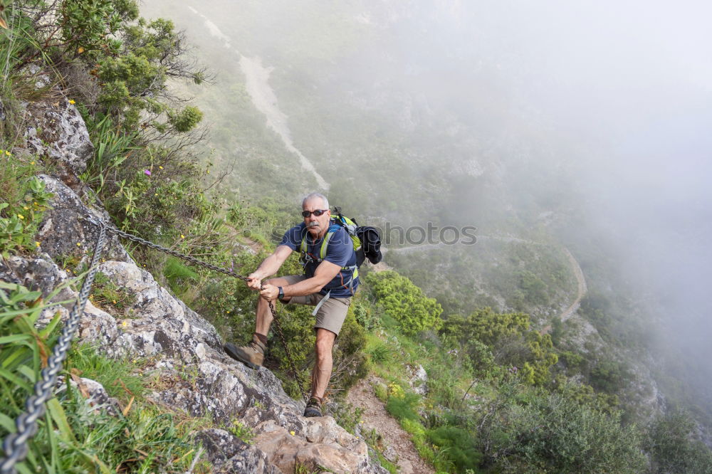 Similar – Young woman with hiking backpack stands on the edge of rain covered valley