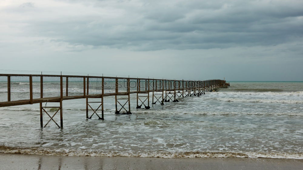 Similar – Steg mit Sonnenschutzdach am Strand bei stürmischer See