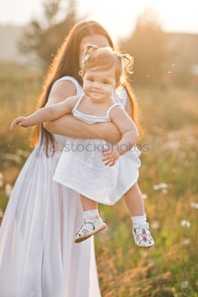 Baby girl standing on a bench hugging to woman