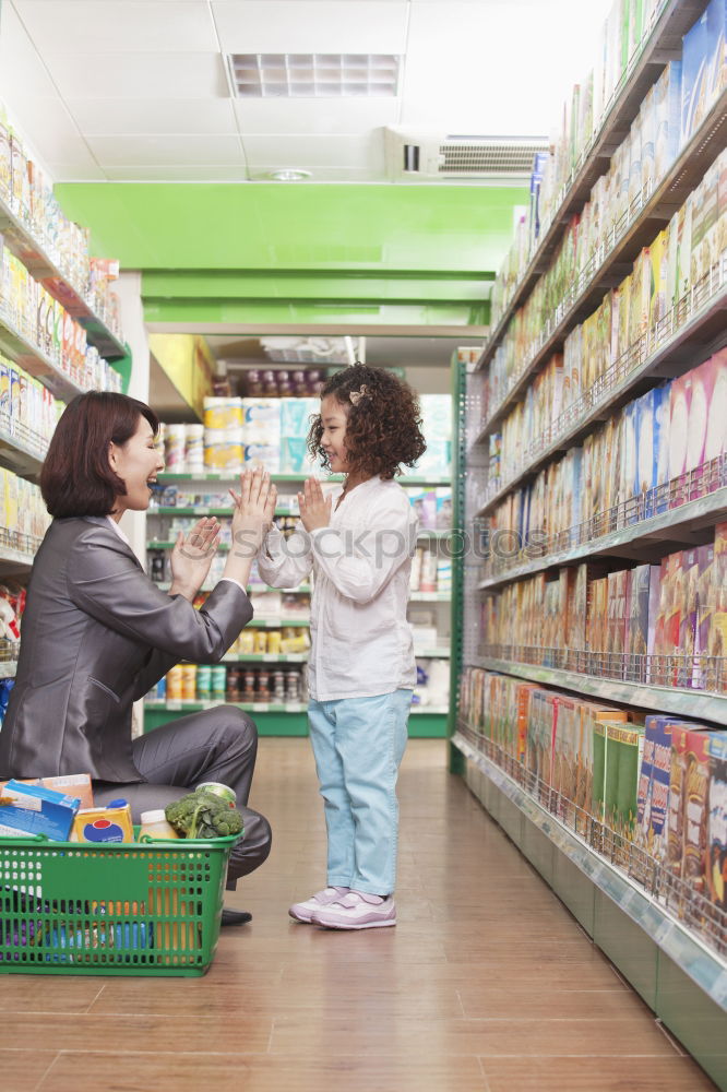 Similar – Image, Stock Photo A smiling middle aged woman in a light blue shirt is standing in a household section of a supermarket. She is holding a tablet and a red shopping basket in her hands. A woman is looking at the shelves, searching for something particular