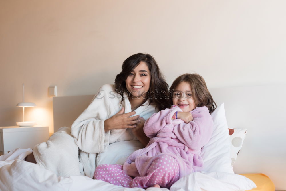 Similar – Three sisters playing with each other lying down in bed at home listening to music