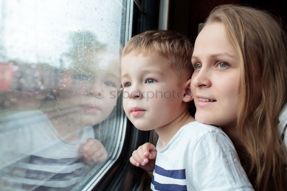 Mother and son looking through a train window as they enjoy a days travel with the small boys face reflected in the glass