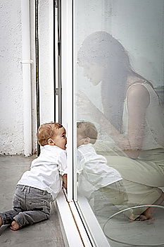 Image, Stock Photo A baby girl studies something on haunches, while her older brother watches her from upstairs sitting on the steps