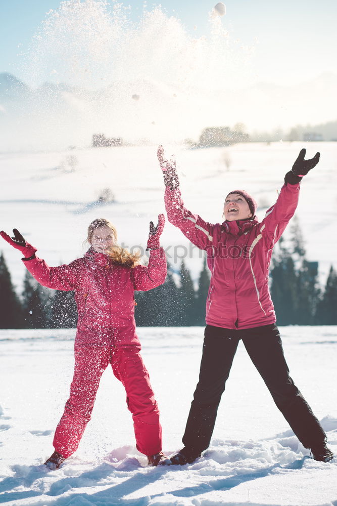 Mother enjoying the snow with her daughter outdoors