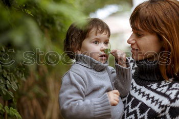 Similar – Mother holding kid on hands in park