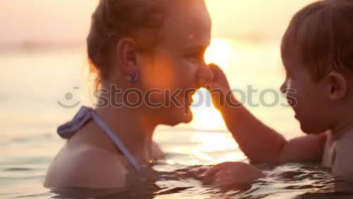 Similar – Image, Stock Photo Mother kissing her young child while bathing in the sea waters during sunset