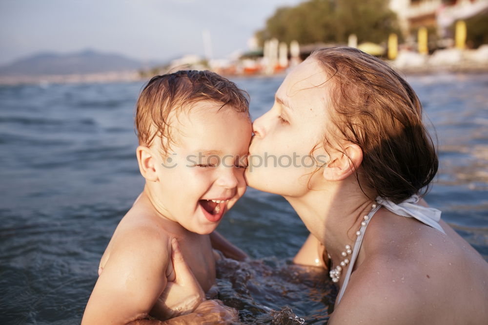 Image, Stock Photo Mother kissing her young child while bathing in the sea waters during sunset